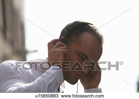 Man listening to headphones outdoors View Large Photo Image Stock Image - Man listening to headphones outdoors. Fotosearch