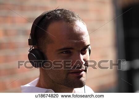 Man listening to headphones outdoors View Large Photo Image Stock Image - Man listening to headphones outdoors. Fotosearch