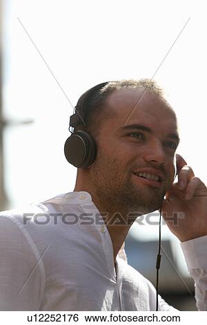 Man listening to headphones outdoors View Large Photo Image Stock Photograph - Man listening to headphones outdoors. Fotosearch