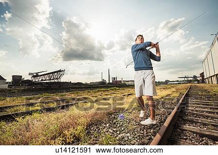 Man playing golf on train tracks View Large Photo Image Stock Image - Man playing golf on train tracks. Fotosearch