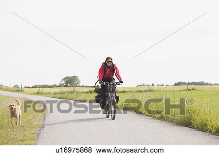 Stock Photo - Man riding bicycle with dog. Fotosearch