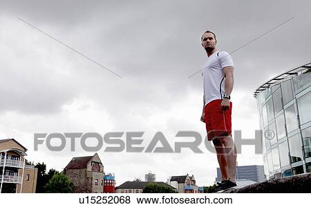 Man standing on wall on city street View Large Photo Image Stock Photo - Man standing on wall on city street. Fotosearch