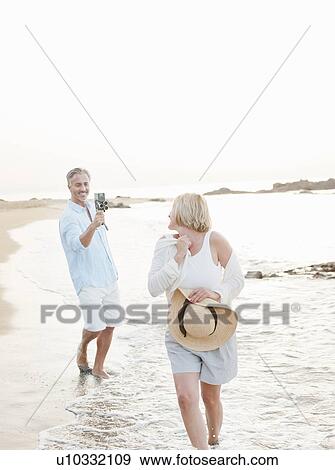 Man taking pictures of wife on beach View Large Photo Image Stock Photo - Man taking pictures of wife on beach. Fotosearch