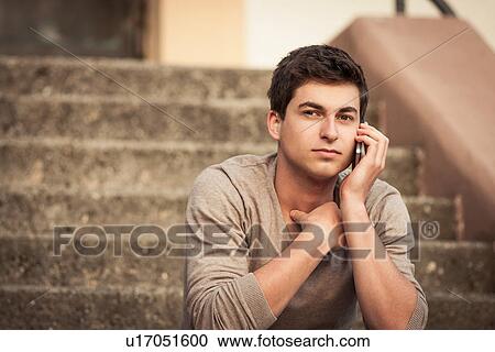 Stock Image - Man talking on cell phone outdoors. Fotosearch