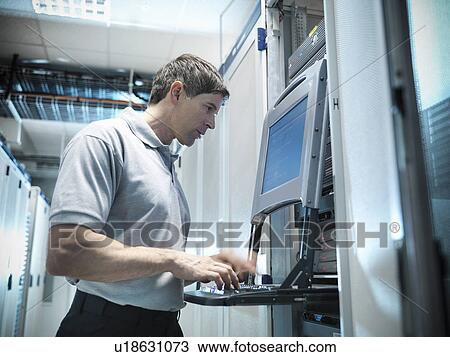 Stock Image - Man working in server room. Fotosearch