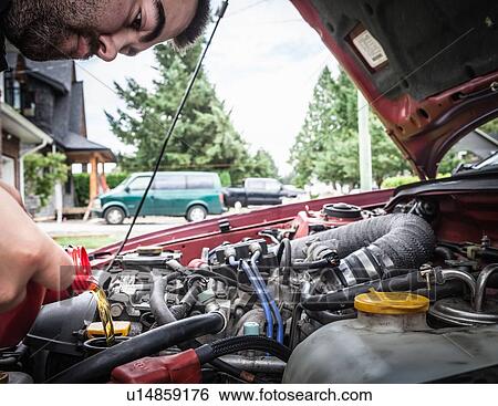 Stock Photograph - Man working on car engine. Fotosearch