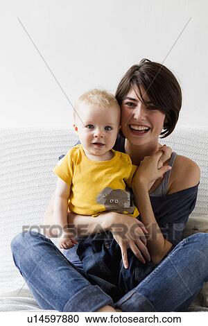Mother and baby sitting on bed View Large Photo Image Stock Image - Mother and baby sitting on bed. Fotosearch