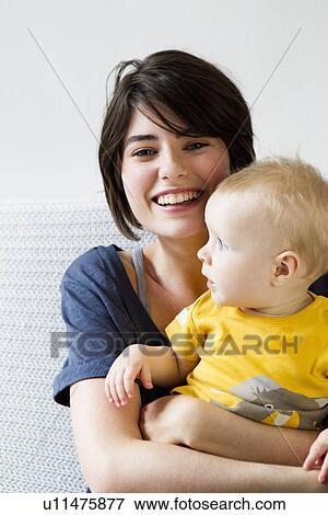 Stock Photo - Mother and baby sitting on bed. Fotosearch