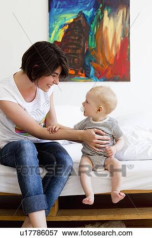 Mother and baby sitting on couch View Large Photo Image Stock Photo - Mother and baby sitting on couch. Fotosearch