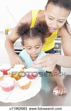 Stock Image - Mother and daughter baking together. Fotosearch