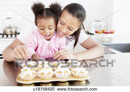 Stock Image - Mother and daughter baking together. Fotosearch