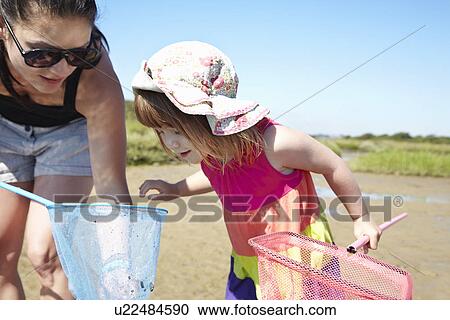 Stock Image - Mother and daughter fishing with nets. Fotosearch
