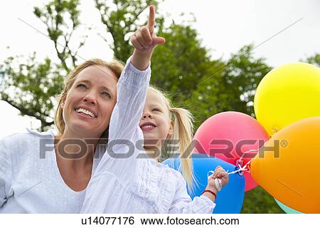 Stock Photograph - Mother and daughter holding balloons. Fotosearch