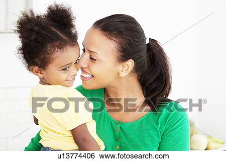Stock Photograph - Mother and daughter hugging in kitchen. Fotosearch