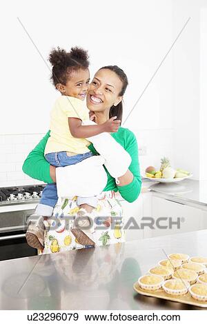 Stock Photo - Mother and daughter laughing in kitchen. Fotosearch
