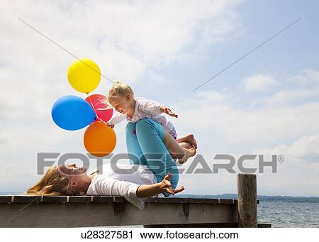 Stock Image - Mother and daughter playing on pier. Fotosearch