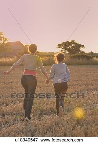 Stock Photo - Mother and daughter running in field. Fotosearch