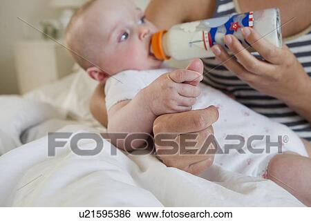 Stock Photograph - Mother bottle feeding baby. Fotosearch