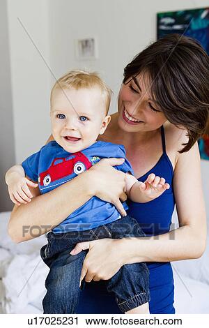Mother holding baby in bedroom View Large Photo Image Stock Image - Mother holding baby in bedroom. Fotosearch
