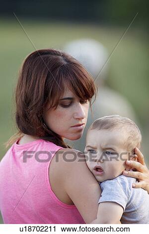 Stock Image - Mother holding crying baby outdoors. Fotosearch