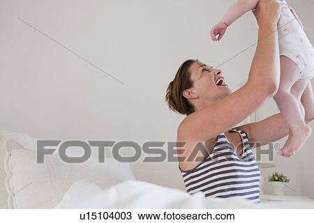 Mother playing with baby in bed View Large Photo Image Stock Image - Mother playing with baby in bed. Fotosearch