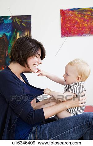 Stock Photo - Mother playing with baby in living room. Fotosearch