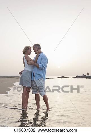 Older couple hugging in waves on beach View Large Photo Image Stock Image - Older couple hugging in waves on beach. Fotosearch