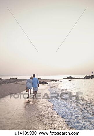 Older couple walking in waves on beach View Large Photo Image Stock Image - Older couple walking in waves on beach. Fotosearch