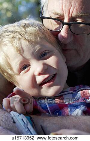 Stock Image - Older man kissing grandson outdoors. Fotosearch