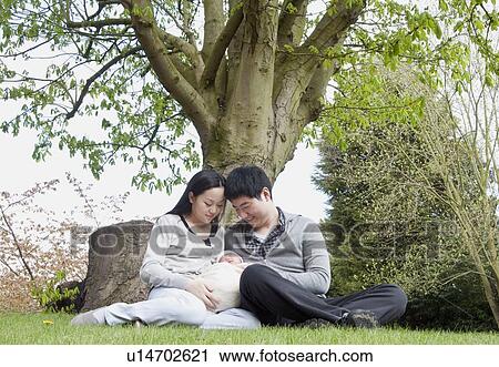 Parents holding sleeping baby in park View Large Photo Image Stock Image - Parents holding sleeping baby in park. Fotosearch