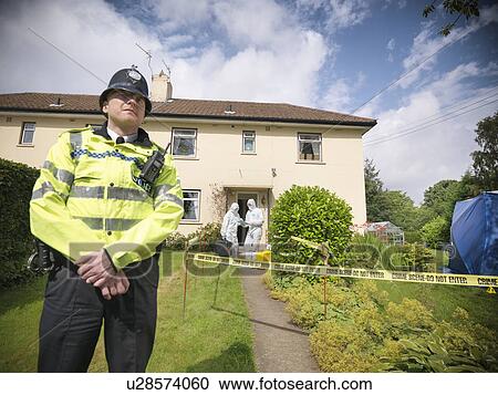 Stock Image - Policeman guarding forensic crime scene. Fotosearch