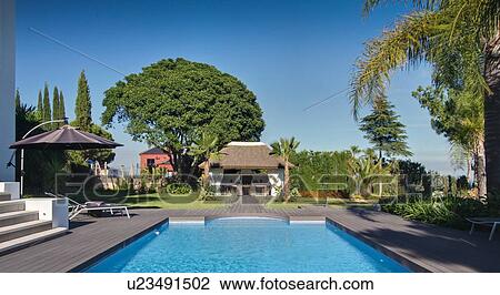 Stock Image - Pool outside tropical villa. Fotosearch