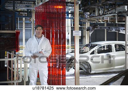 Stock Photography - Portrait of worker inspecting car body in car factory. Fotosearch