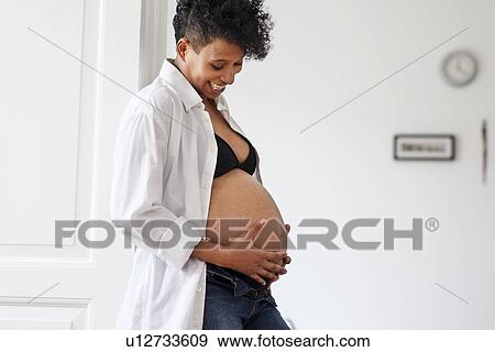 Pregnant woman cradling her belly View Large Photo Image Stock Photo - Pregnant woman cradling her belly. Fotosearch