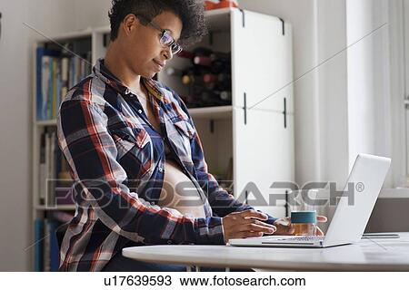 Pregnant woman using laptop in kitchen View Large Photo Image Stock Image - Pregnant woman using laptop in kitchen. Fotosearch
