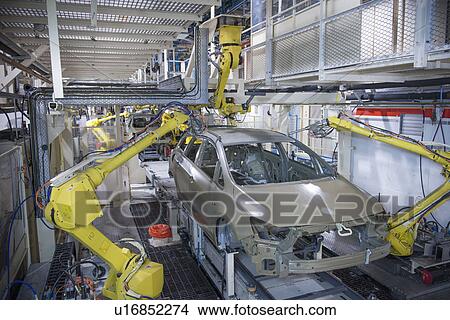Picture - Robots applying sealant to cars in car factory. Fotosearch