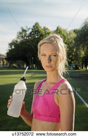 Stock Image - Runner drinking water in park. Fotosearch