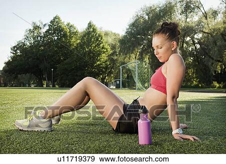 Stock Photo - Runner resting on grass in park. Fotosearch