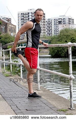 Stock Image - Runner stretching on city street. Fotosearch