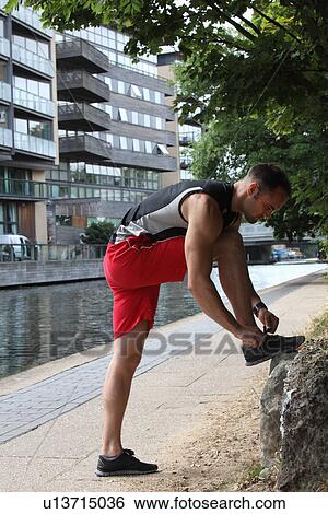 Stock Photograph - Runner tying his shoes on city street. Fotosearch