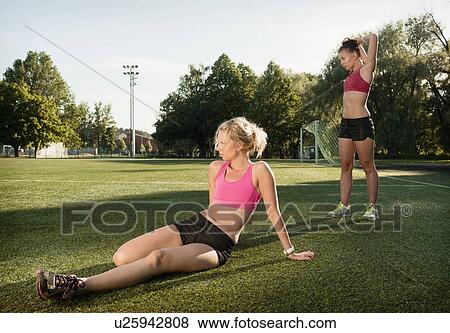 Runners stretching on grass in park View Large Photo Image Stock Photo - Runners stretching on grass in park. Fotosearch