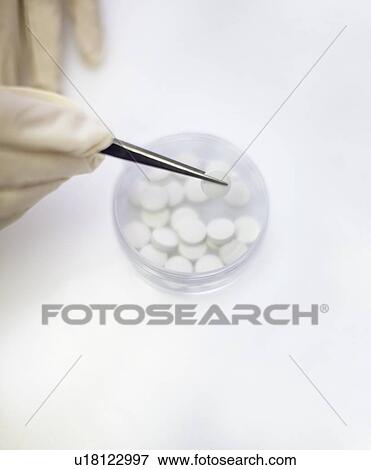 Stock Photo - Scientist holding pill with tweezers. Fotosearch