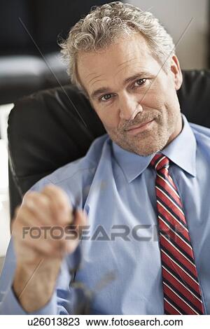 Stock Image - Serious businessman sitting at desk. Fotosearch