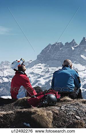 Skiers resting on rocky mountaintop View Large Photo Image Stock Photograph - Skiers resting on rocky mountaintop. Fotosearch