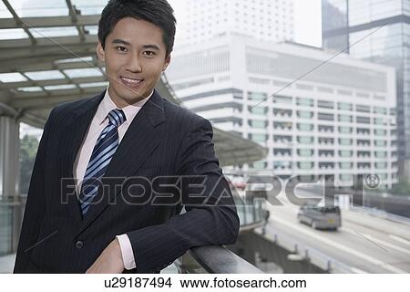 Picture - Smiling businessman leaning on banister. Fotosearch