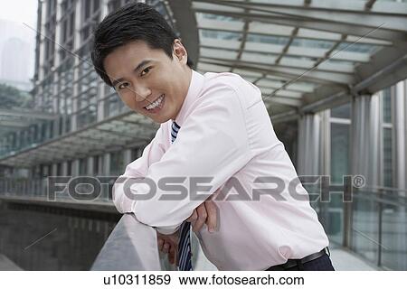 Smiling businessman leaning on banister View Large Photo Image Stock Photo - Smiling businessman leaning on banister. Fotosearch