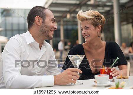 Stock Photography - Smiling couple having drinks outdoors. Fotosearch
