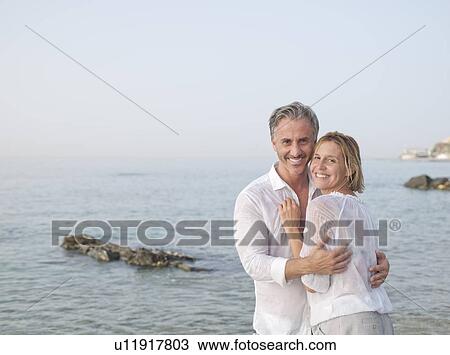 Smiling couple hugging on beach View Large Photo Image Stock Image - Smiling couple hugging on beach. Fotosearch