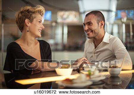 Stock Image - Smiling couple relaxing at bar. Fotosearch