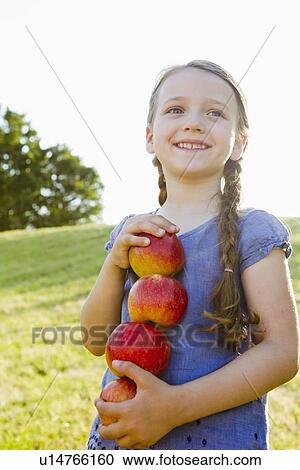 Smiling girl carrying apples outdoors View Large Photo Image Stock Image - Smiling girl carrying apples outdoors. Fotosearch